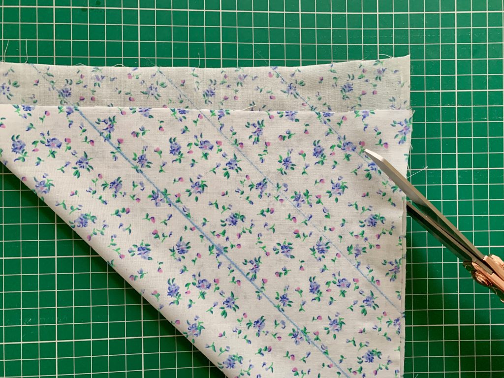 fabric folded on the diagonal to create the bias with blue lines marked at 2 inches intervals.