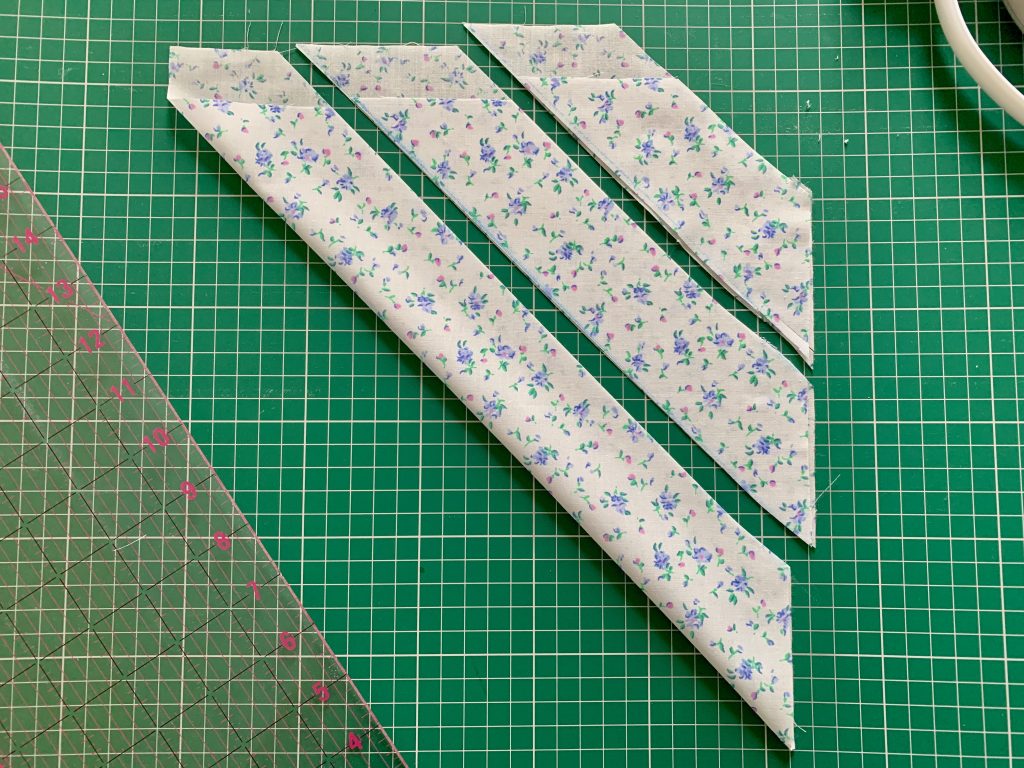 bias strips in blue and white floral fabric on a green cutting mat.